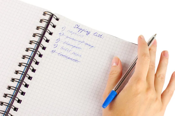 Woman\'s hand holding a notebook with a shopping list close-up