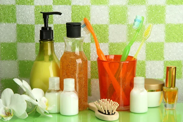 Bath accessories on shelf in bathroom on green tile wall background