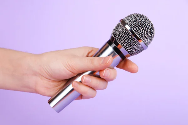 Silver microphone in hand on purple background