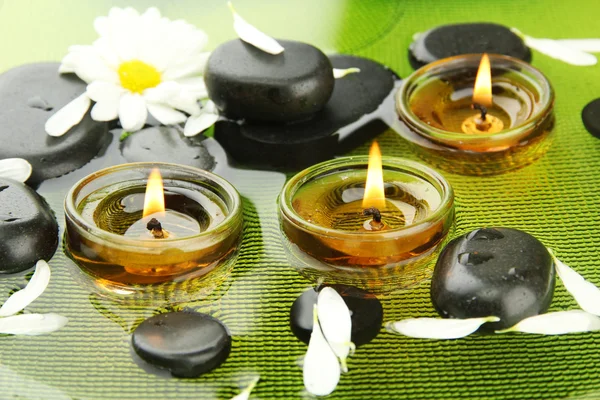 Spa stones with flowers and candles in water on plate