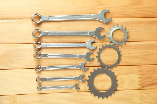 Metal cogwheels and spanners on wooden background