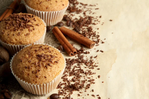 Tasty muffin cakes with chocolate, spices and coffee seeds, on beige background