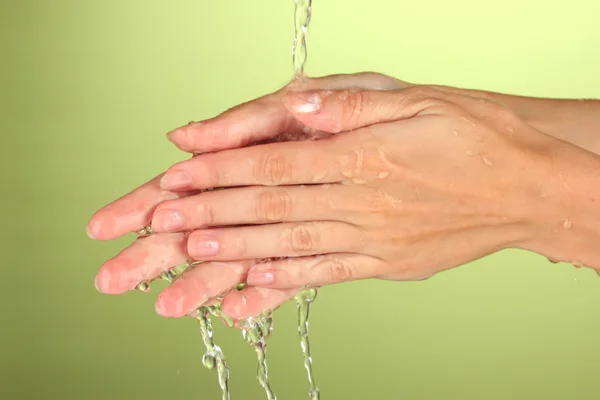 Washing hands on green background close-up