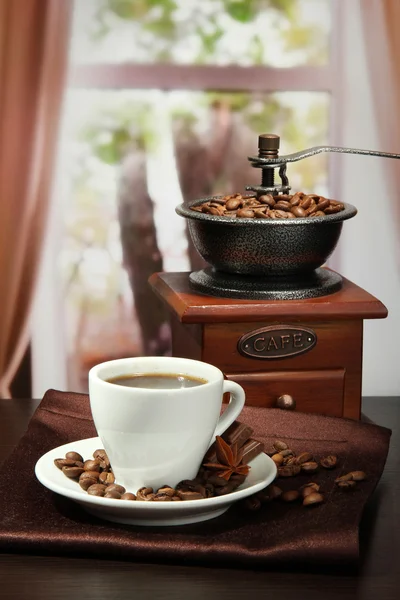 Cup of coffee, grinder and coffee beans in cafe
