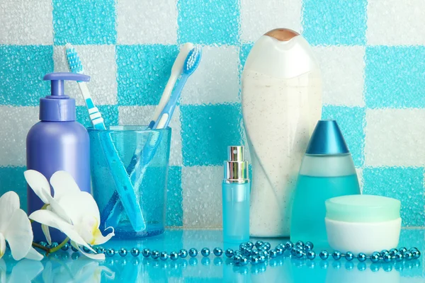 Bath accessories on shelf in bathroom on blue tile wall background