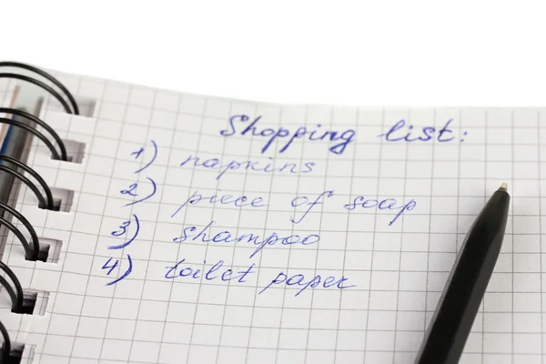 Shopping list in a notebook on white background close-up