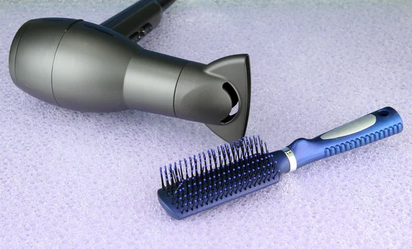 Hair dryer and comb brush, on purple background