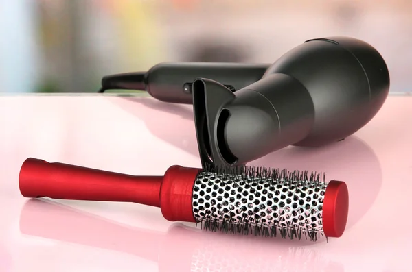 Hair dryer and comb brush, on table in beauty salon