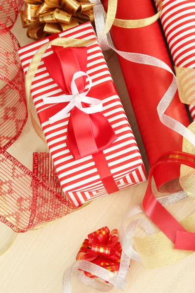 Rolls of Christmas wrapping paper with ribbons, bows on wooden background