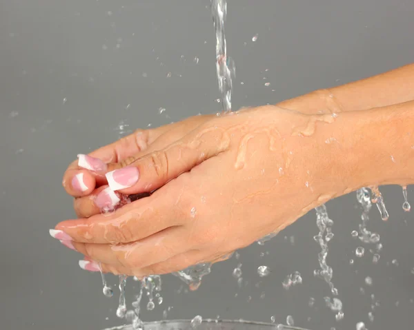Washing woman\'s hands on gray background close-up