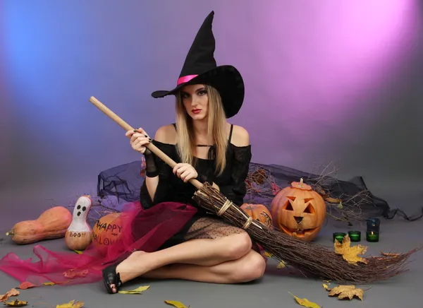 Halloween witch with broom on color background