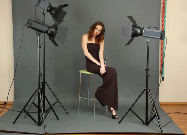 Beautiful professional female model resting between shots in photography studio shoot set-up