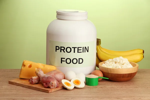 Jar of protein powder and food with protein, on green background