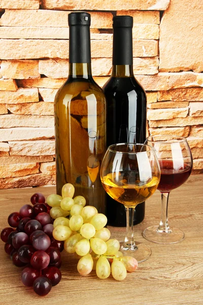 Composition of wine and grapes on table on brick wall background