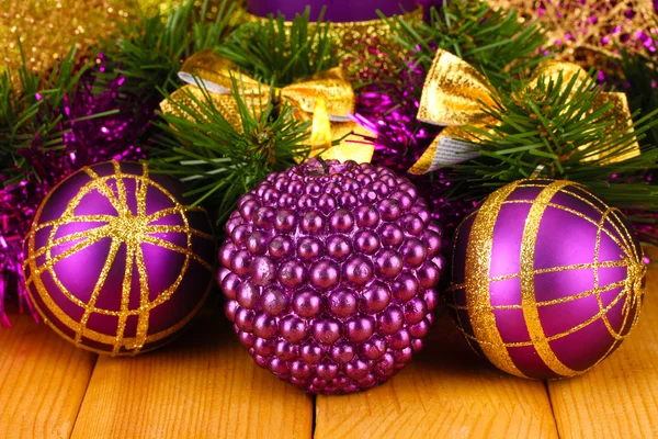 Christmas composition with candles and decorations in purple and gold colors on wooden background