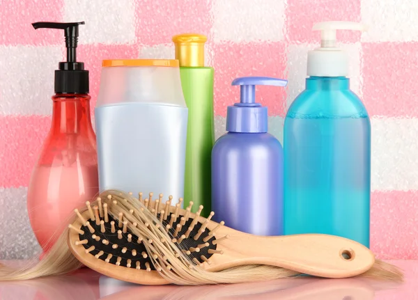 Comb brush with hair and cosmetic bottles in bathroom — Stock Photo #19733329
