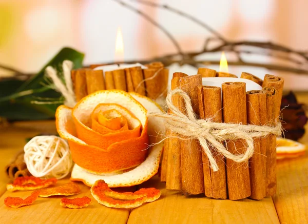 Decorative rose from dry orange peel and burning candles on wooden table