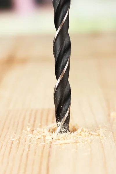 Close-up image of drilling hole on wooden plank, on bright background