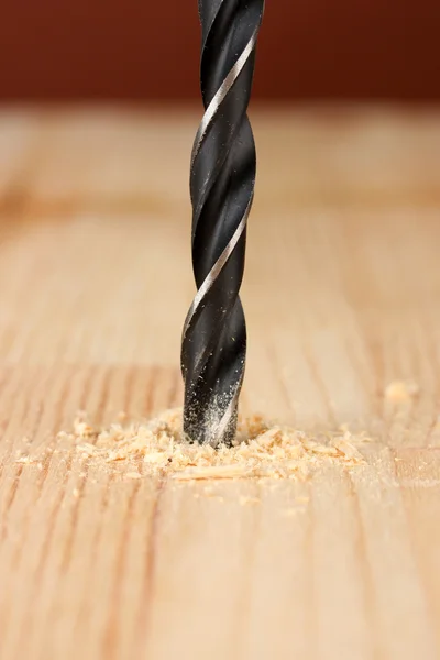 Close-up image of drilling hole on wooden plank, on color background