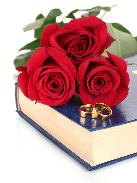 Wedding rings with roses on bible isolated on white