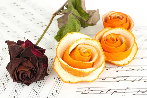 Dried rose and decorative roses from dry orange peel on musical notes