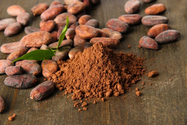 Cocoa beans and cocoa powder on wooden background