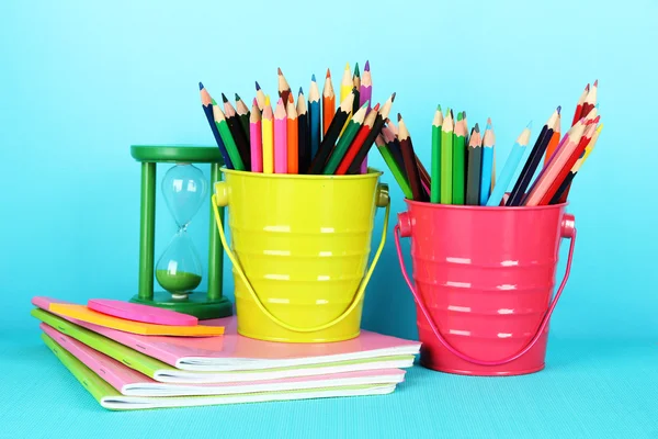 Colorful pencils with school supplies on blue background