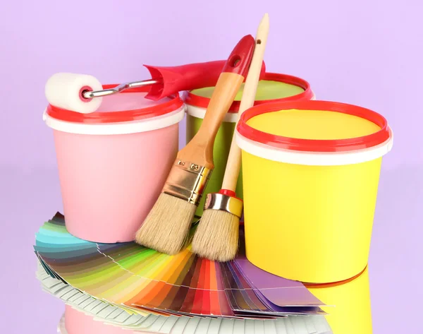 Set for painting: paint pots, brushes, paint-roller, palette of colors on lilac background