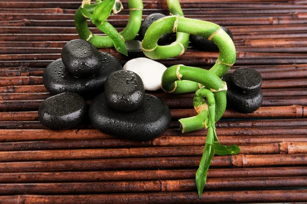 Beautiful bamboo branches with stones for spa on wooden table