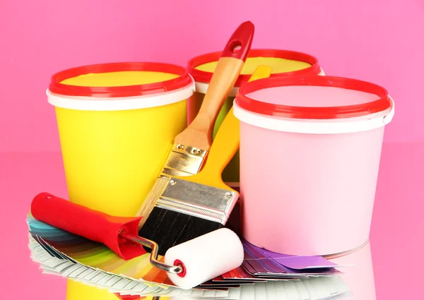 Set for painting: paint pots, brushes, paint-roller, palette of colors on pink background