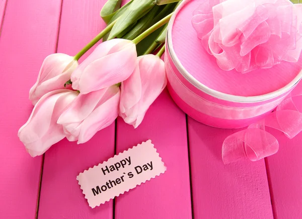 Beautiful bouquet of tulips and gift for Mother\'s Day on pink wooden background