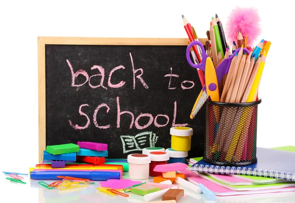 The words 'Back to School' written in chalk on the small school desk with various school supplies close-up isolated on white