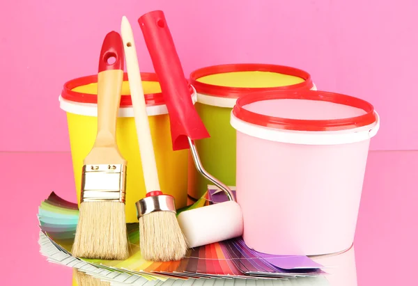 Set for painting: paint pots, brushes, paint-roller, palette of colors on pink background