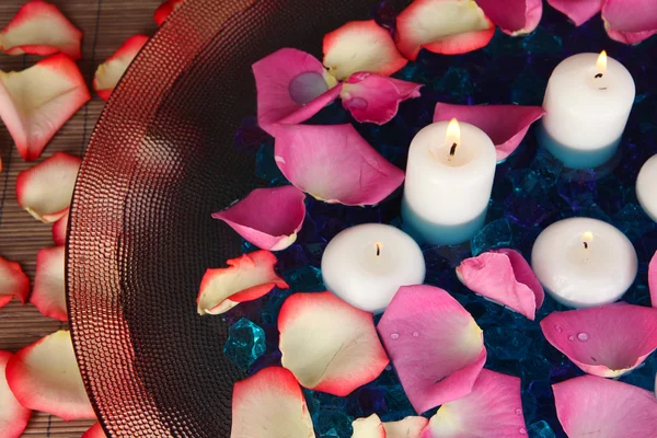 Rose petals and candles in water in vase close-up