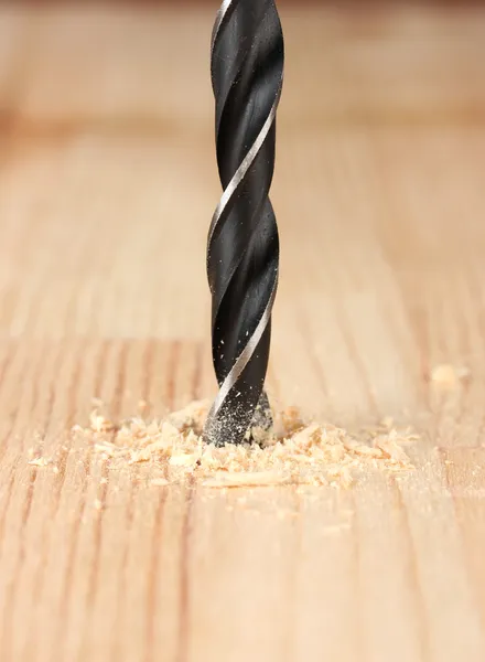 Close-up image of drilling hole on wooden plank, on color background