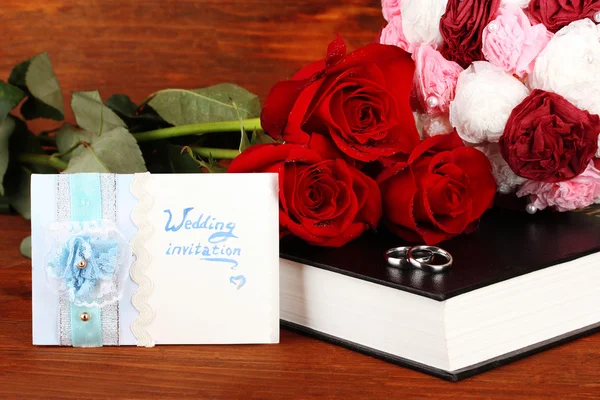 Wedding rings on bible with roses on wooden background