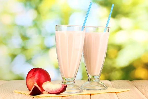 Peach milk shakes on wooden table on bright background
