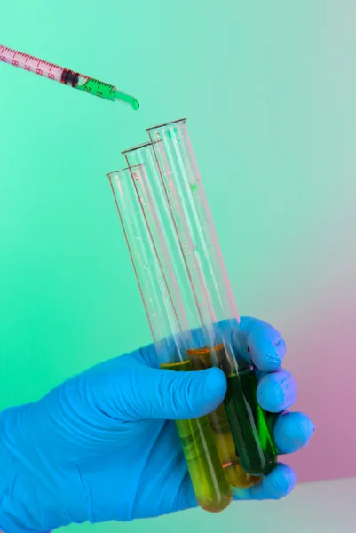 Hands in gloves and test tubes on blue-purple background