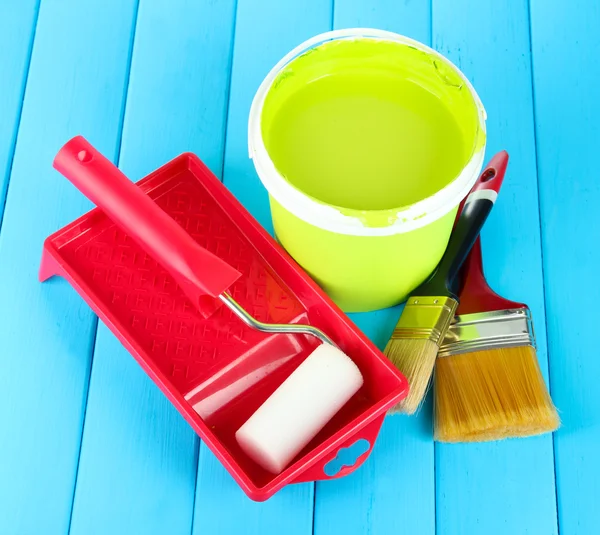 Set for painting: paint pot, brushes, paint-roller on blue wooden table