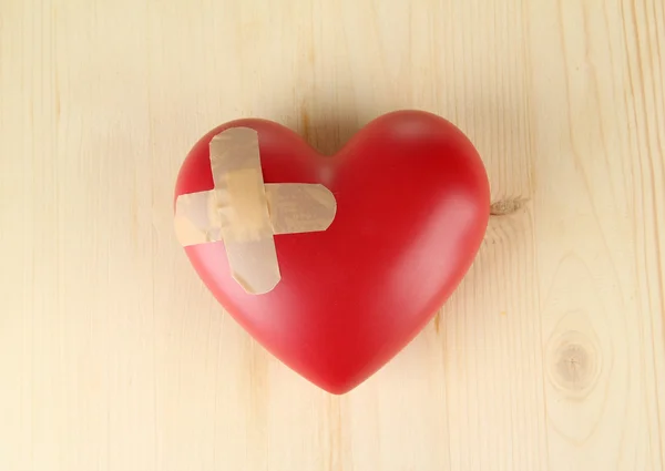 Heart with plaster, on wooden background