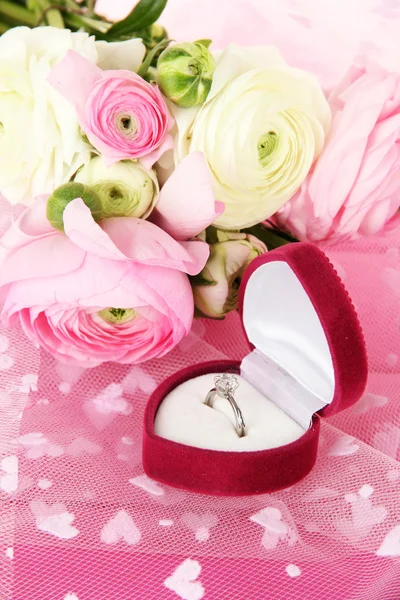 Ranunculus (persian buttercups) and engagement ring, on pink cloth