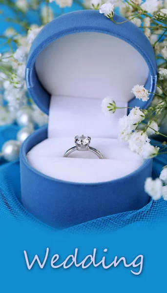 Flowers and engagement ring on blue cloth