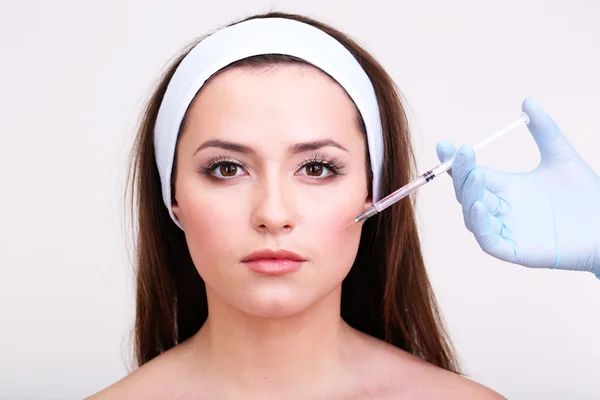Young woman receiving plastic surgery injection on her face close up