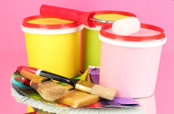 Set for painting: paint pots, brushes, paint-roller, palette of colors on pink background