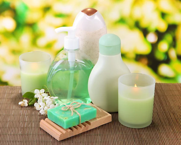 Cosmetics bottles and natural handmade soap on green background