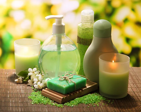 Cosmetics bottles and natural handmade soap on green background