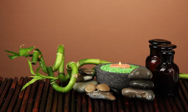 Still life with green bamboo plant and stones, on bamboo mat on color background