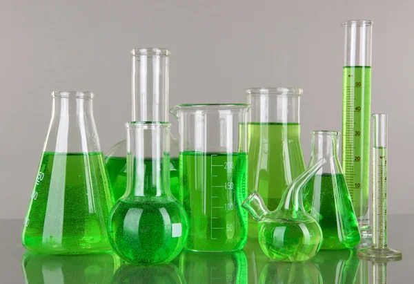 Test-tubes with green liquid on gray background
