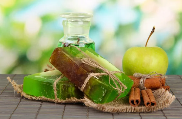 Hand made soap and ingredients for soap making on bamboo mat, on green background