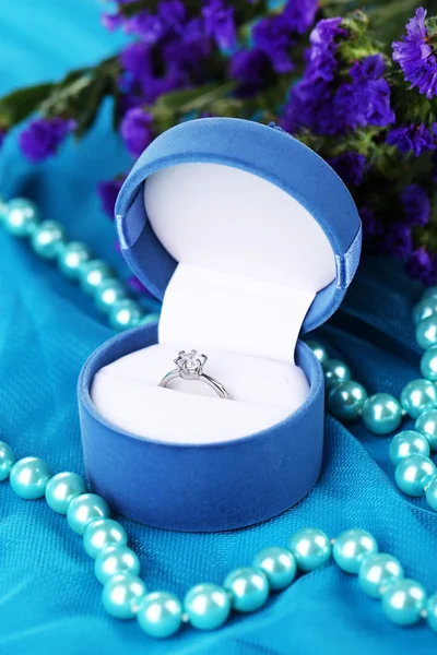 Flowers and engagement ring on blue cloth